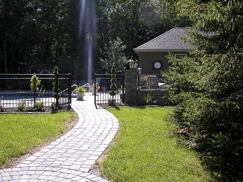 Picture of a beautiful Ornamental aluminum pool fence installed between stone pillars in a customers backyard